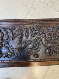 A sculptured walnut panel with putti, allegorical characters and human-headed dragons around an ecusson, presumably France, 16th C.