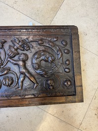 A sculptured walnut panel with putti, allegorical characters and human-headed dragons around an ecusson, presumably France, 16th C.