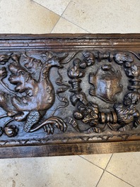 A sculptured walnut panel with putti, allegorical characters and human-headed dragons around an ecusson, presumably France, 16th C.