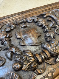 A sculptured walnut panel with putti, allegorical characters and human-headed dragons around an ecusson, presumably France, 16th C.