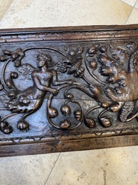 A sculptured walnut panel with putti, allegorical characters and human-headed dragons around an ecusson, presumably France, 16th C.