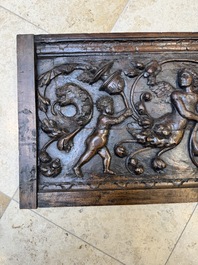 A sculptured walnut panel with putti, allegorical characters and human-headed dragons around an ecusson, presumably France, 16th C.