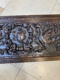 A sculptured walnut panel with putti, allegorical characters and human-headed dragons around an ecusson, presumably France, 16th C.