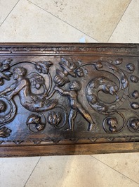 A sculptured walnut panel with putti, allegorical characters and human-headed dragons around an ecusson, presumably France, 16th C.