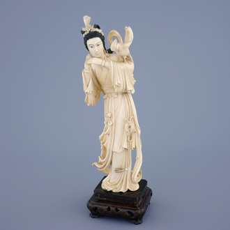 A Chinese carved ivory figure of Guanyin with a bird on wooden base, 19th C.