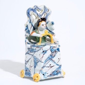 A Dutch Delft polychrome group of a child seated on a toilet, 18th C.
