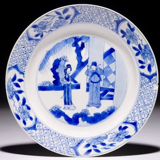 Une assiette en porcelaine de Chine bleu et blanc à décor de personnages dans un jardin, marque et période de Kangxi