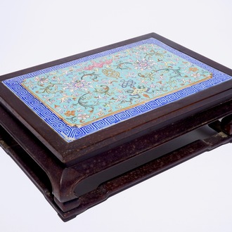 A Chinese famille rose enamel tile plaque mounted in a wood stand, 19th C.