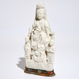 Een Chinees Dehua blanc de Chine model van Guanyin met een kind en acolieten, Kangxi