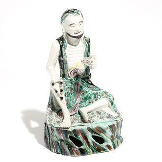 A Chinese verte biscuit model of a luohan with a scroll, Kangxi