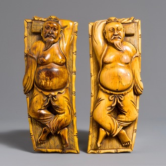 A pair of Chinese carved ivory figures of resting men on a bed, 19th C.