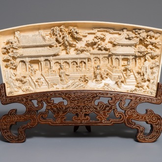 A Chinese carved ivory panel with figures in a landscape on inlaid wooden stand, first half 20th C.