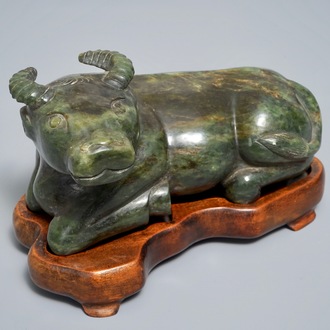 A Chinese spinach green jade model of an ox on wooden stand, 19/20th C.
