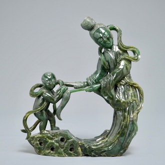 A Chinese spinach green jade group of Guanyin with a child, 19th C.