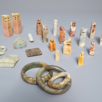Een lot van 23 Chinese zegels, armbanden, amuletten en gesp in jade, zeepsteen en hardsteen, 19/20e eeuw