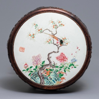 Une plaque en porcelaine de Chine famille rose dans un socle en bois, 19/20ème