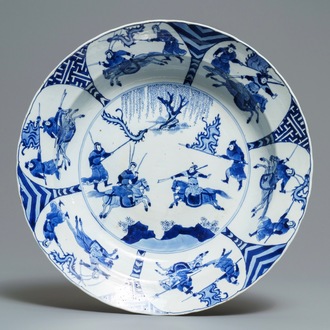 Un grand plat en porcelaine de Chine bleu et blanc à décor de guerriers, marque de Chenghua, Kangxi