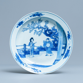 Un plat en porcelaine de Chine en bleu et blanc à décor de figures dans un jardin, Kangxi