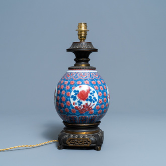 Een Chinese blauw-witte en koperrode vaas met vergulde bronzen lampmontuur, 19e eeuw