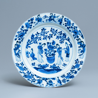 Een Chinese blauw-witte schotel met dames bij een jardinière, Kangxi