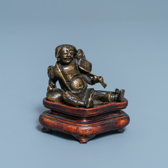 Un poids à rouleau figurant Liu Hai en bronze sur socle en bois, Chine, Ming