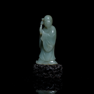 Een Chinese figuur van een onsterfelijke in celadon jade op houten sokkel, Qing