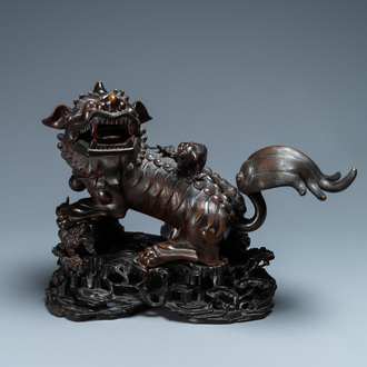 Un modèle d'un lion bouddhiste en bronze sur socle en bois sculpté, Chine, 18ème