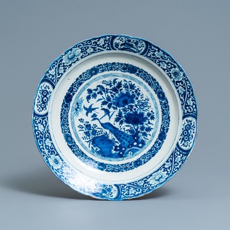 A Dutch Delft blue and white dish with a peacock in a Chinese garden, dated 1693