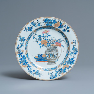 Une assiette en porcelaine de Chine en famille rose et grisaille à décor d'un vase fleuri et de fruits, Yongzheng