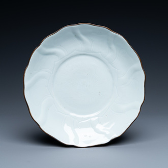 Une assiette moulée en porcelaine de Chine en blanc monochrome à décor incisé de fleurs de lotus, marque et époque de Xuande