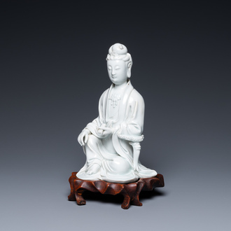 A Chinese Dehua blanc de Chine figure of Guanyin on a wooden stand, 19/20th C.
