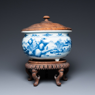 A Chinese blue and white 'landscape' tripod censer with later wooden cover and stand, Kangxi