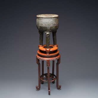 Een grote Chinese driepotige bronzen wierookbrander op houten voet en sokkel, Qing