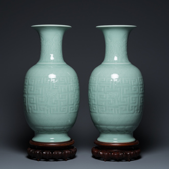Een paar Chinese monochrome celadon vazen met onderglazuur decor op houten sokkels, Qianlong merk, 18/19e eeuw