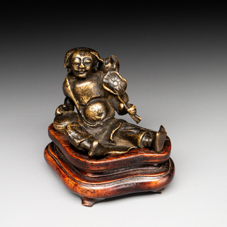 A Chinese bronze paperweight in the form of 'Shi De 拾得' on wooden stand, 16th C.