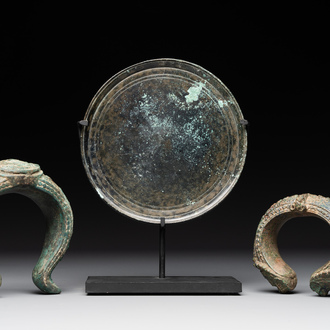 A bronze mirror, a bracelet with a royal or noble emblem and a bronze bracelet with two tiger heads, Cambodia, 12th C.