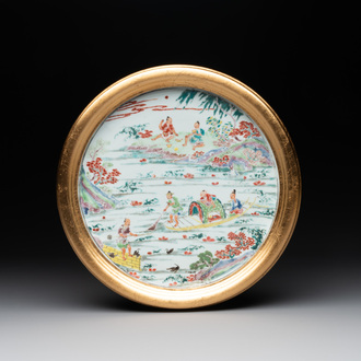 A Chinese famille rose plate with figures in a river landscape in gilt wooden frame, Yongzheng