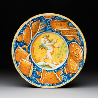 A polychrome Italian maiolica plate with a putto surrounded by trophies, Pesaro, 16th C.