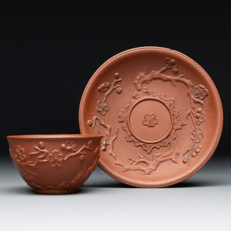 A Chinese Yixing stoneware cup and saucer with plum blossom relief design, Kangxi