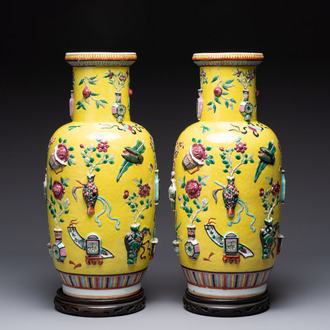 A pair of Chinese famille rose yellow-ground relief-decorated vases with wooden stands, 19th C.