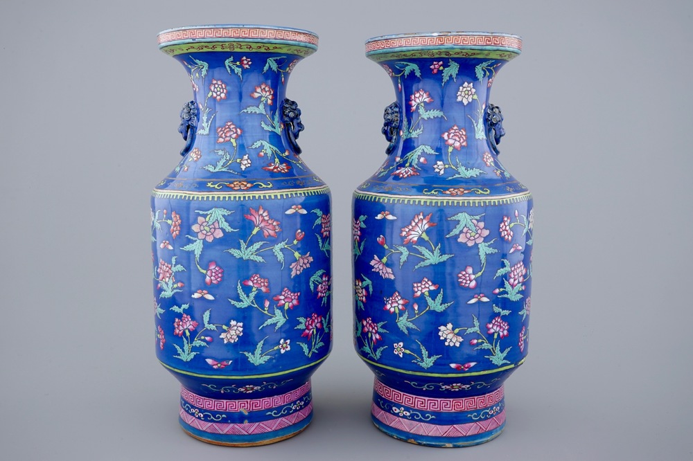 A pair of Chinese blue ground famille rose vases with flowers, 19th C.