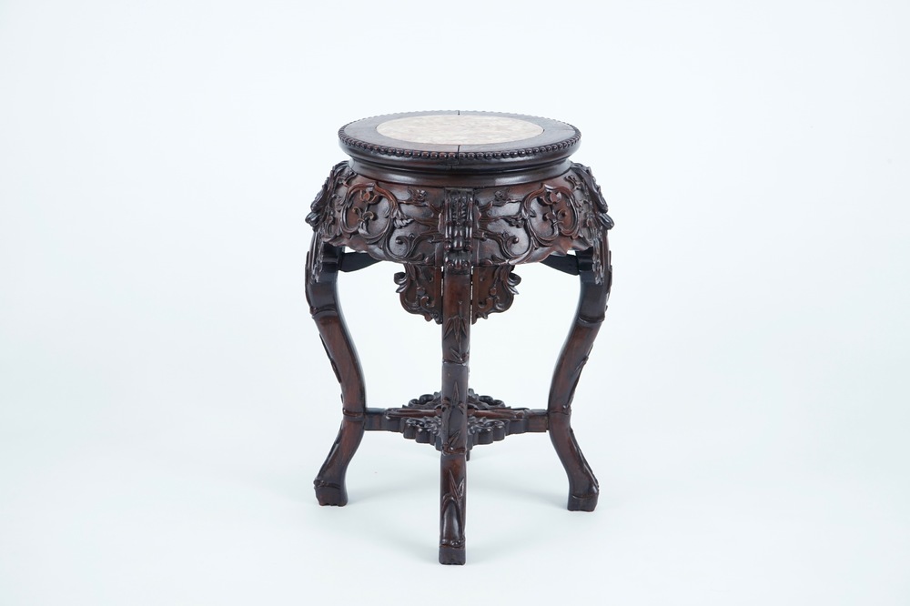 A carved round Chinese wood stand with marble top, 19/20th C.