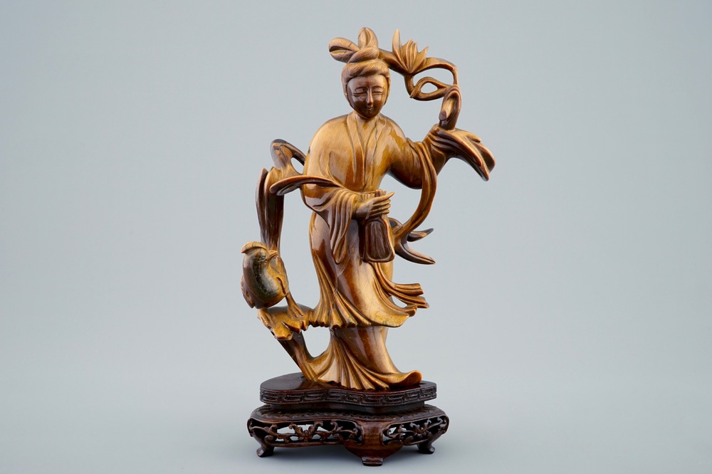 Een Chinese gesculpteerd Guanyin in tijgeroog op houten basis, 19/20e eeuw