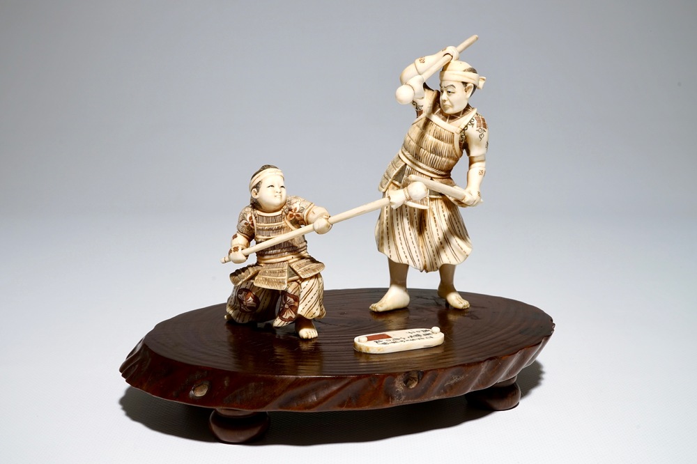 A Japanese ivory group of a warrior and his pupil, on a wooden base, Meiji, signed