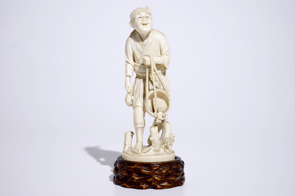 A Japanese ivory okimono of a fisherman on wooden base, Meiji, 19th C., signed