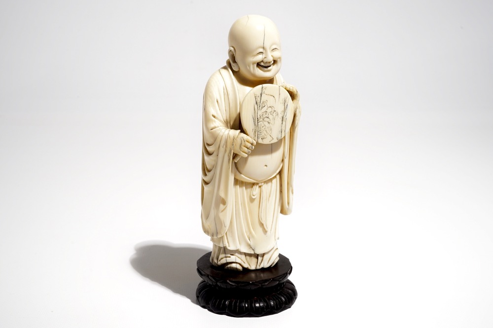 A Chinese carved ivory figure of Buddha holding a fan, on lotus-shaped base, 19th C.