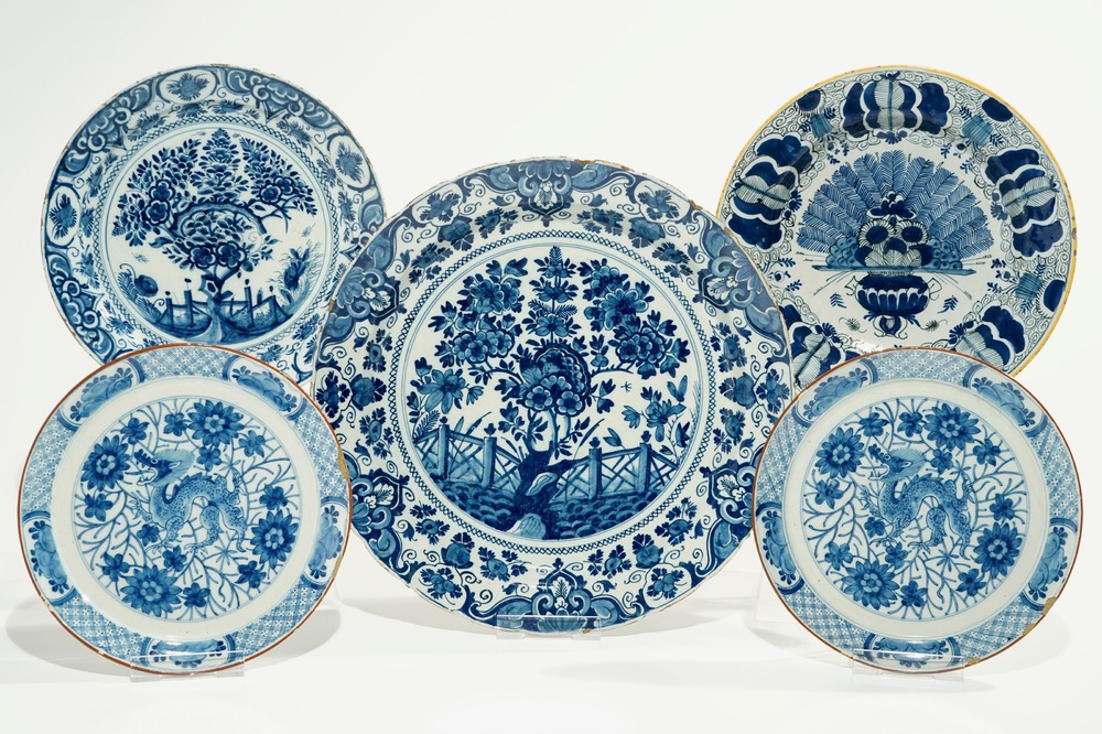 Five Dutch Delft blue and white plates with dragons, tea trees and a peacock's tail, 17/18th C.