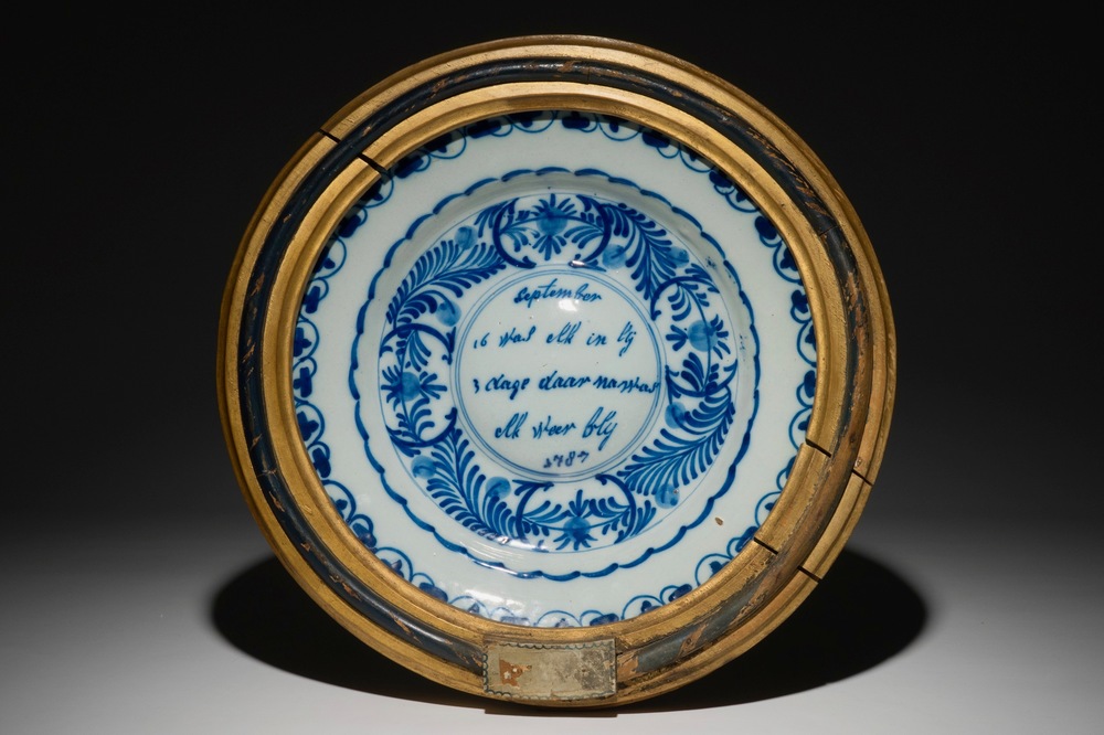 Un plat &agrave; ombilic en fa&iuml;ence de Delft bleu et blanc encadr&eacute;, dat&eacute; 1787