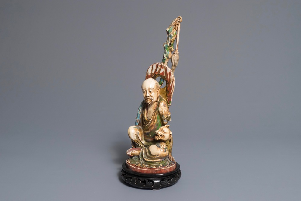 A polychrome Chinese ivory group of a sage with a tiger, 19/20th C.
