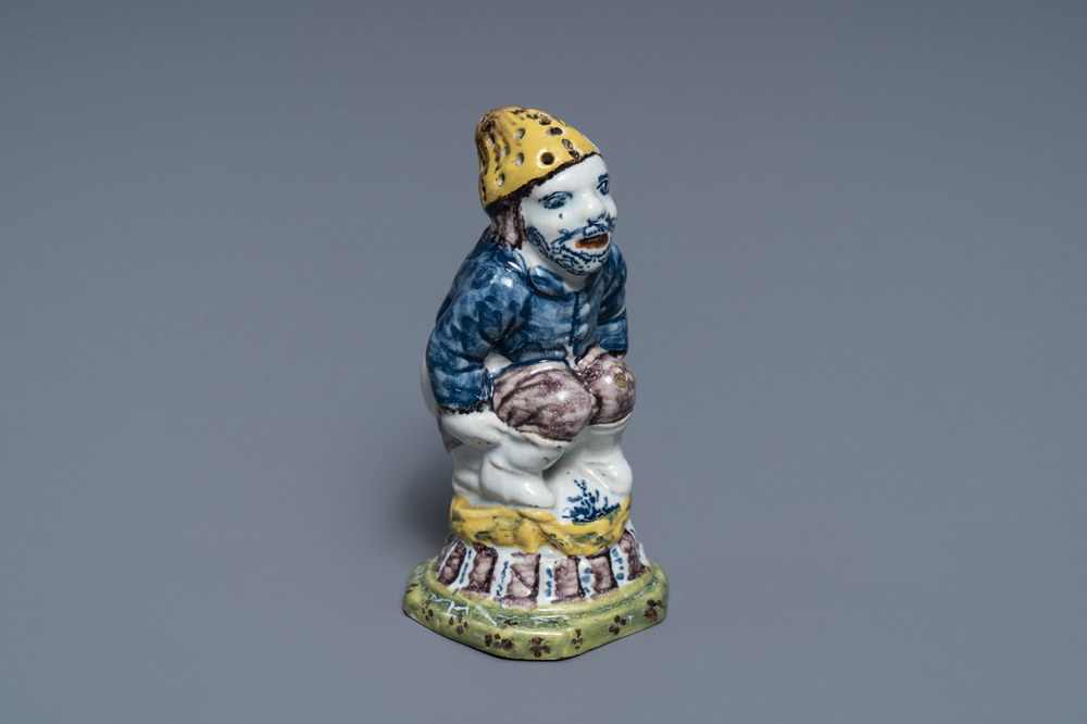 A rare polychrome Dutch Delft caster in the shape of a pooping man, 18th C.